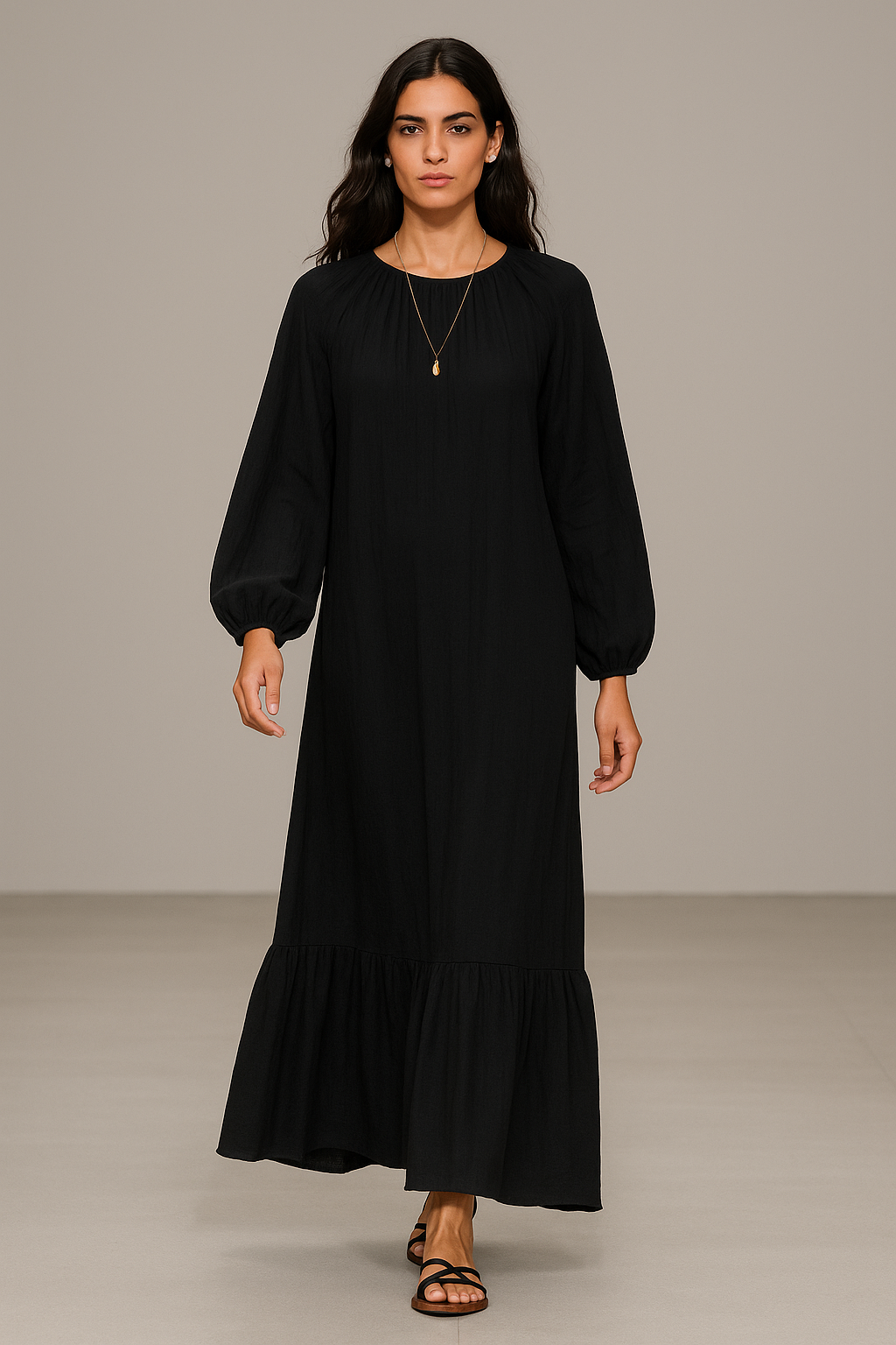 Brunette model in her 20s walking a runway in a black maxi dress with puff sleeves, ruffled hem, and flat sandals.