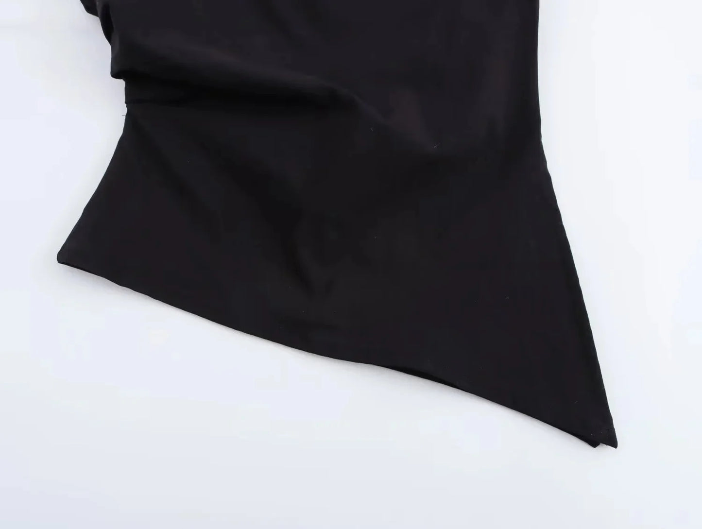 close up of asymmetrical detail on black top on a white background