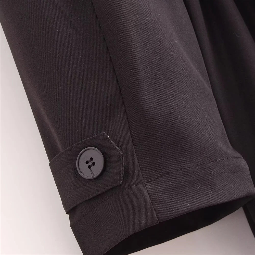 Close-up of The Noir Trench coat sleeve with buttoned cuff detail, showcasing clean stitching and structured woven fabric.
