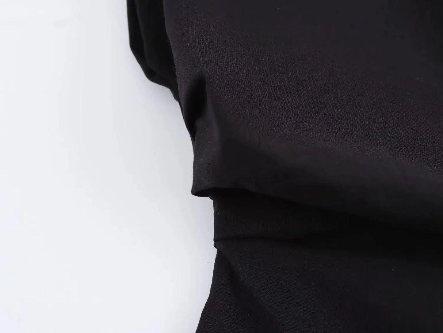 Close-up waist detail of a black garment on a white background