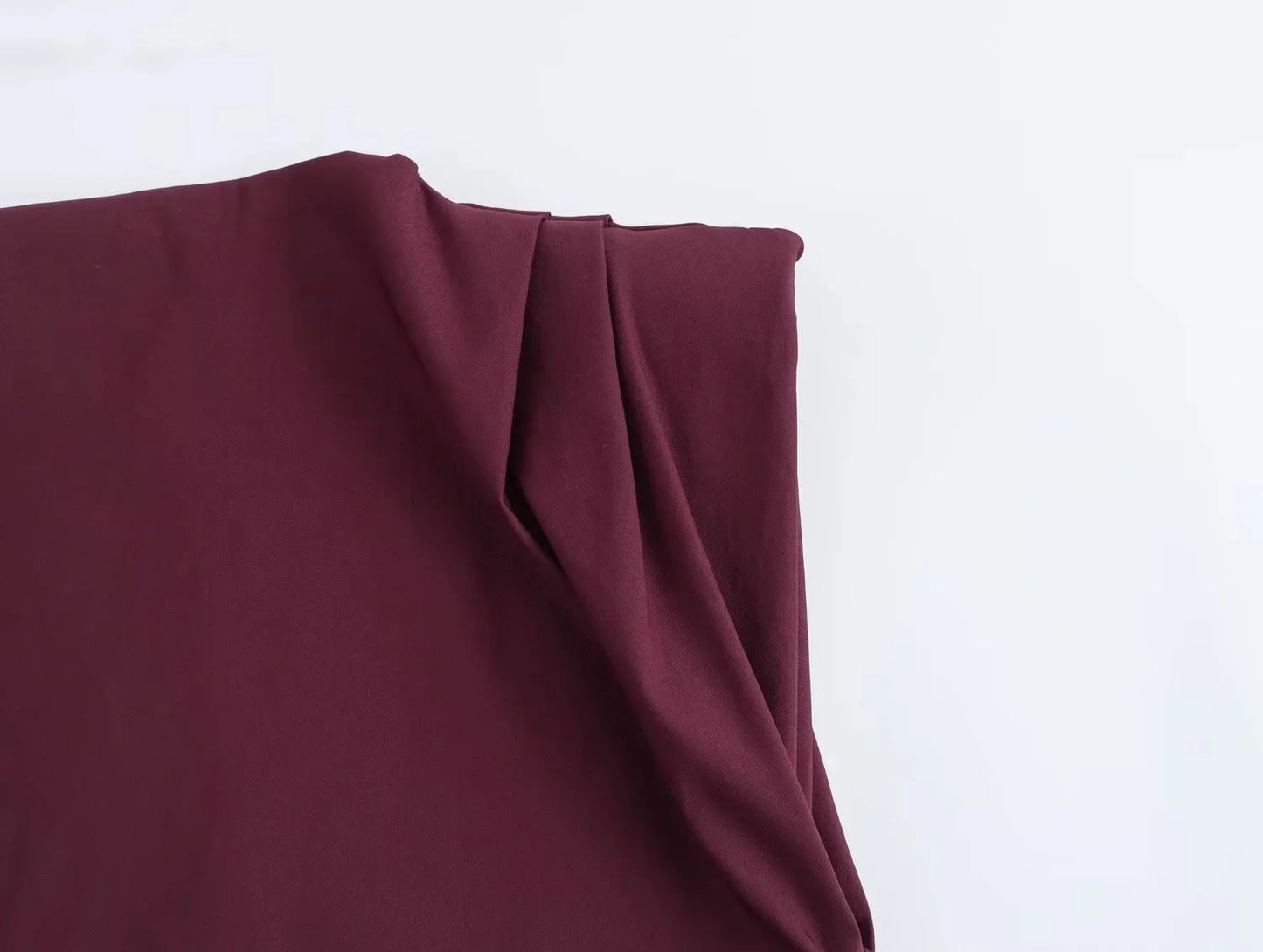Close-up of a wine red top with folds on a white background