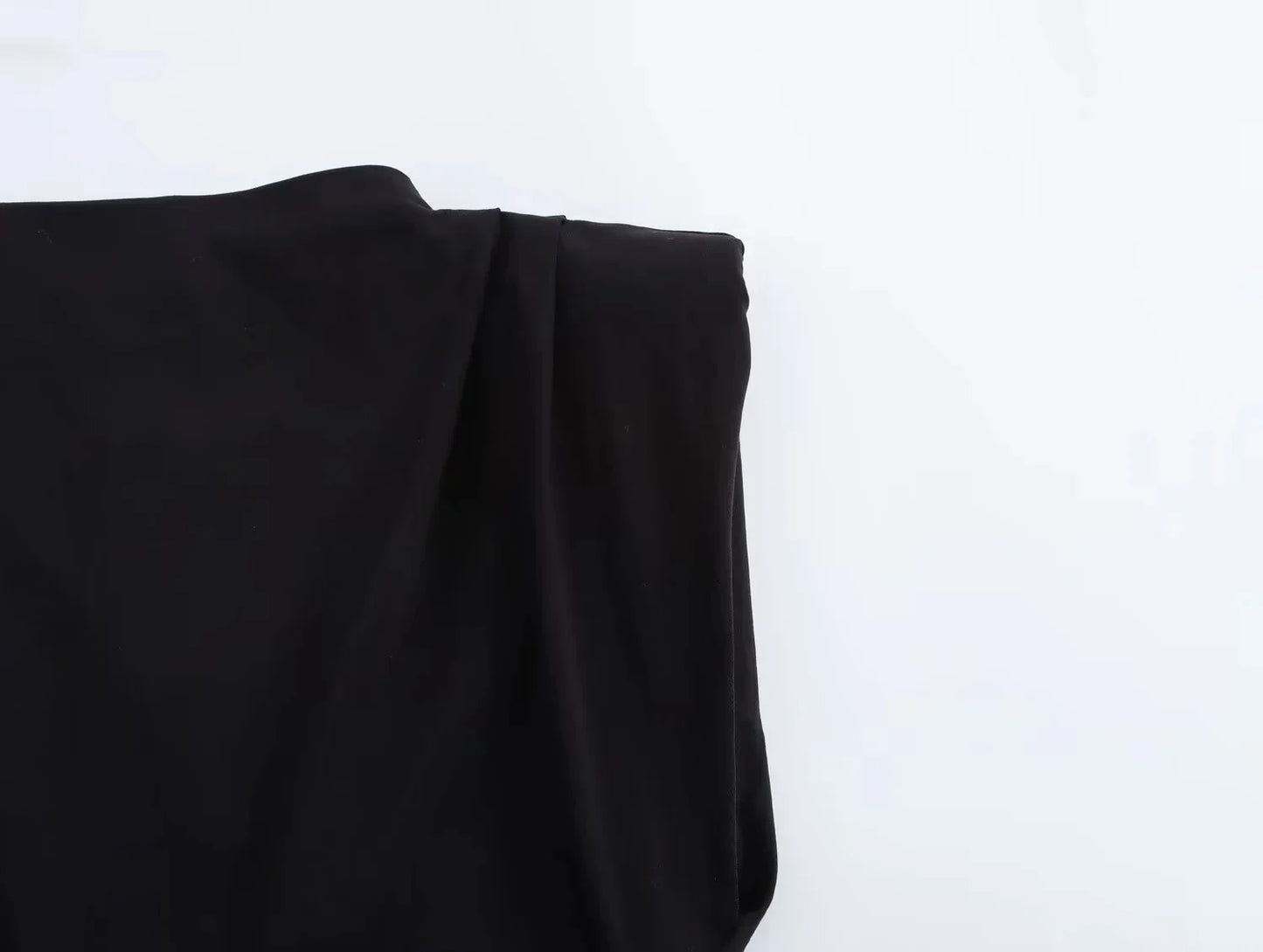 close up of shoulder detail of black top on a white background