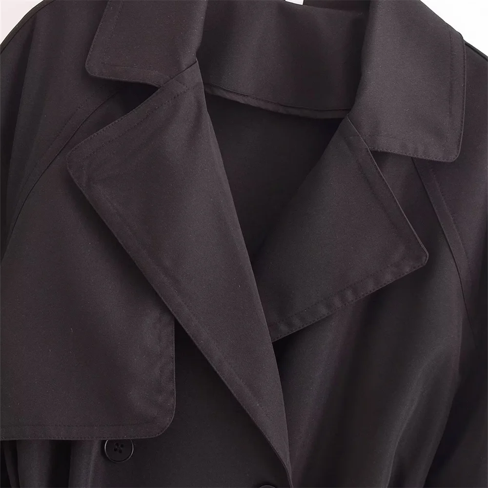 Close-up of trench coat lapels in black, showing the smooth woven fabric and tailored stitching detail