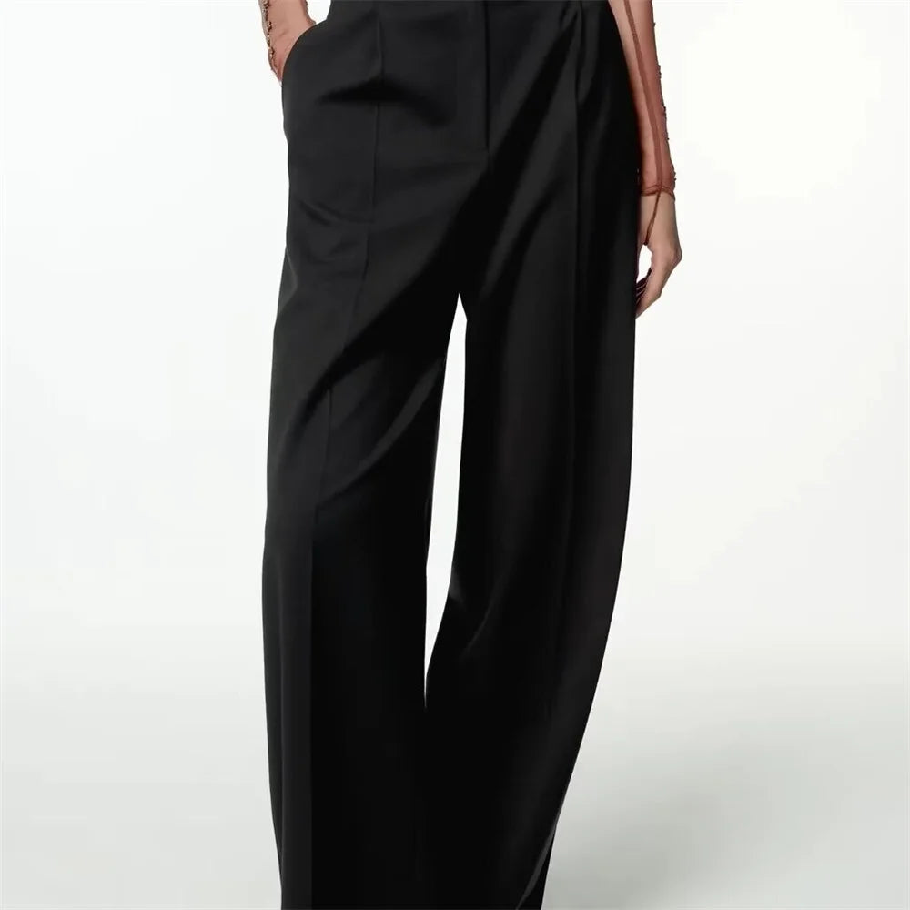 Front view of black Noir by Lina trousers with wide-leg cut and tailored pleats, worn with fitted top