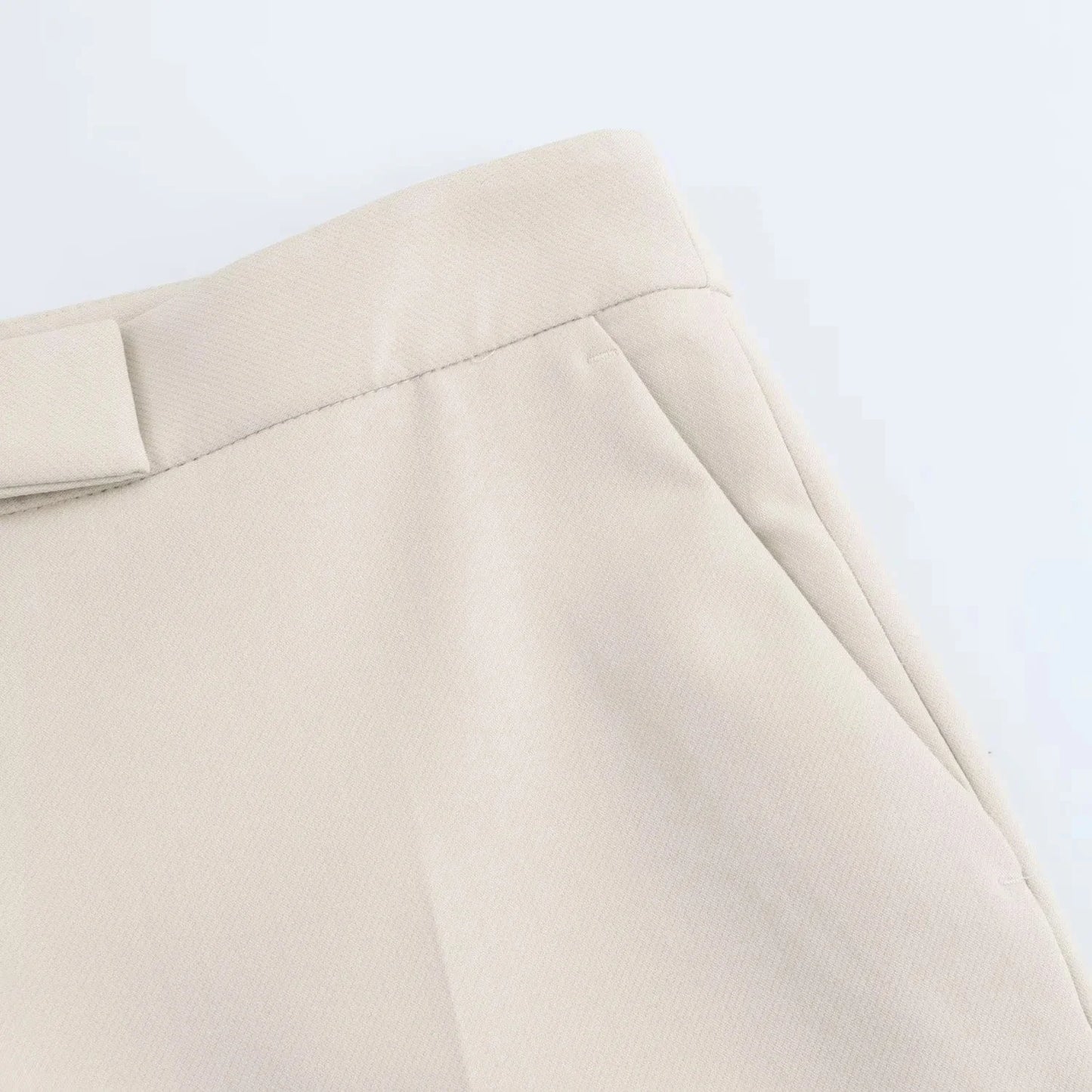 Detail of waistband and slanted pocket on white slim flared trousers from the Valencia Power Suit by Noir by Lina
